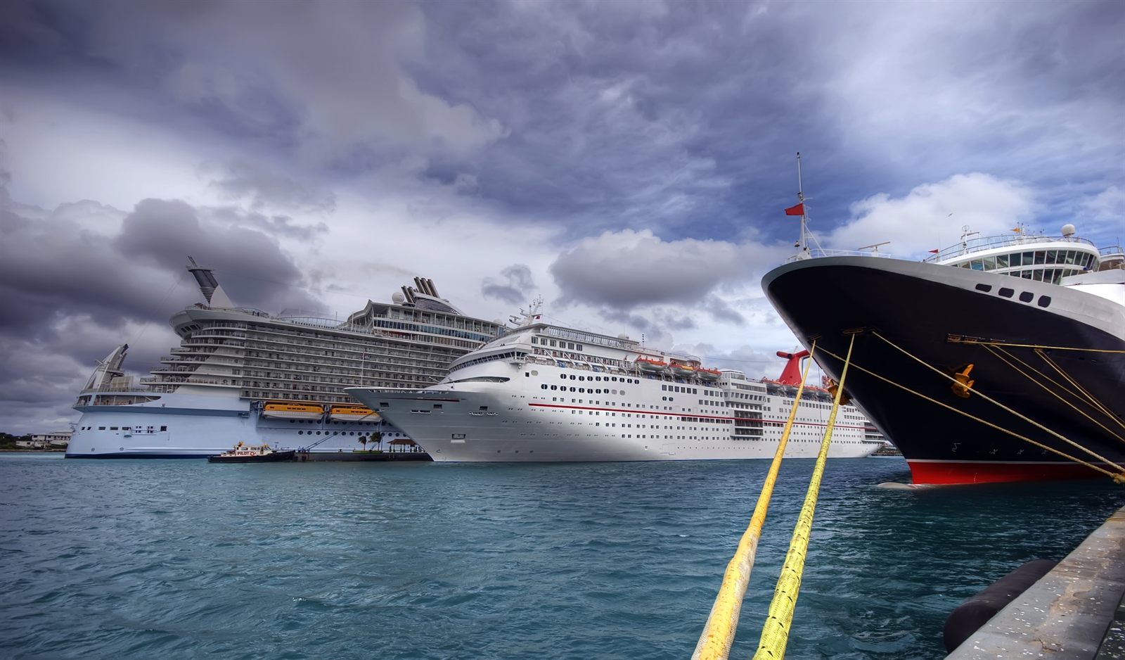 Cruise ships moored at a pier under heavy grey clouds